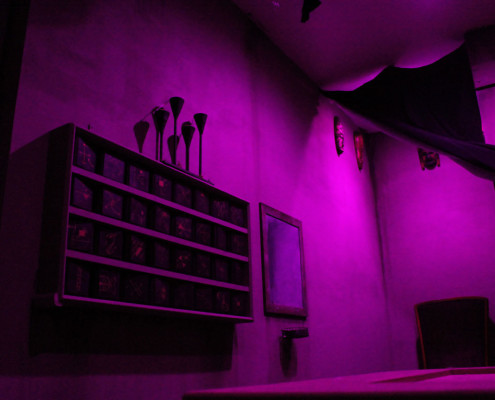 A shadowy room in purple light inside The Vanishing Act